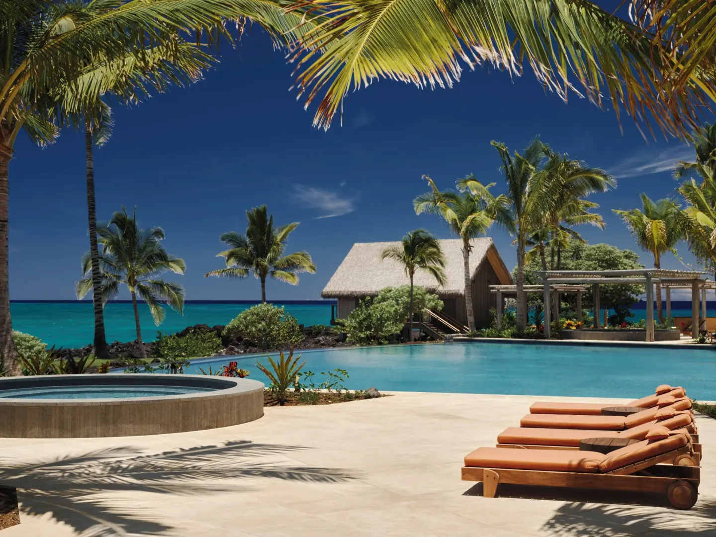 Oceanfront pool deck with loungers and palm shade at Kona Village.