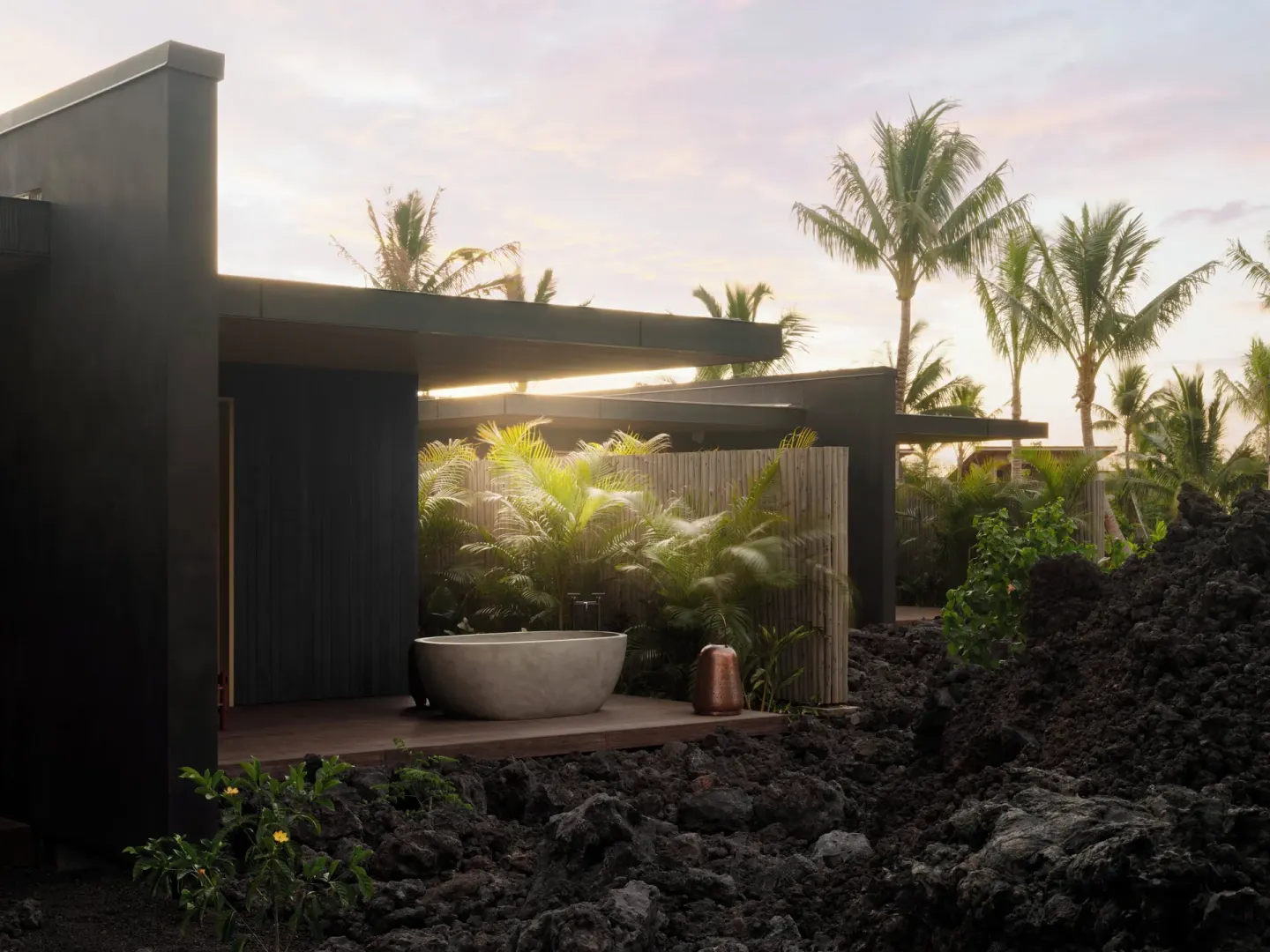 Outdoor soaking tub beside lava rock and palms at Kona Village.