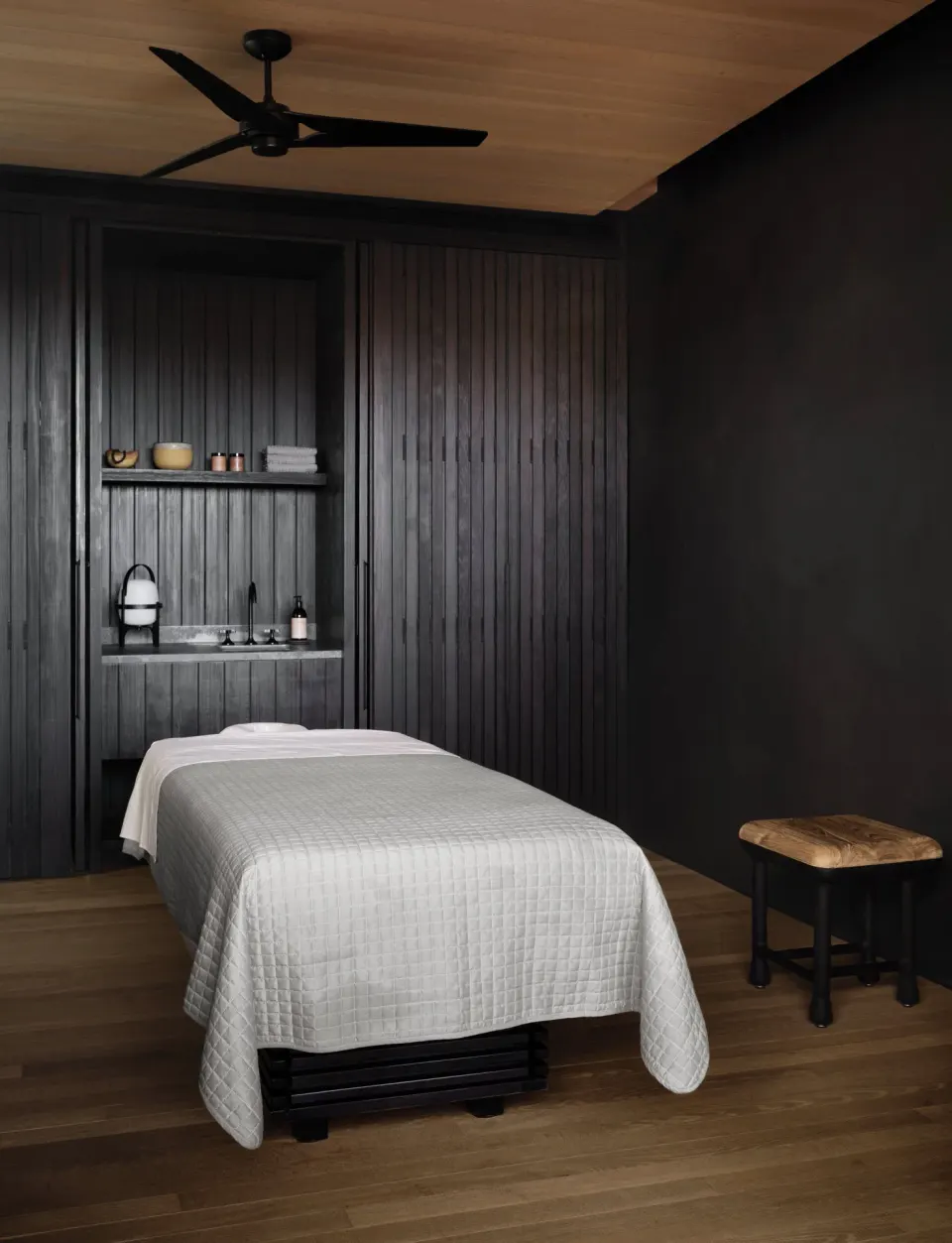 Single spa treatment table in a dark wood treatment room at Kona Village.
