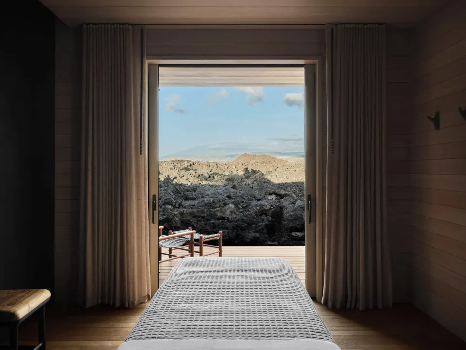 Spa treatment room with a table facing sliding doors and lava rock at Kona Village.