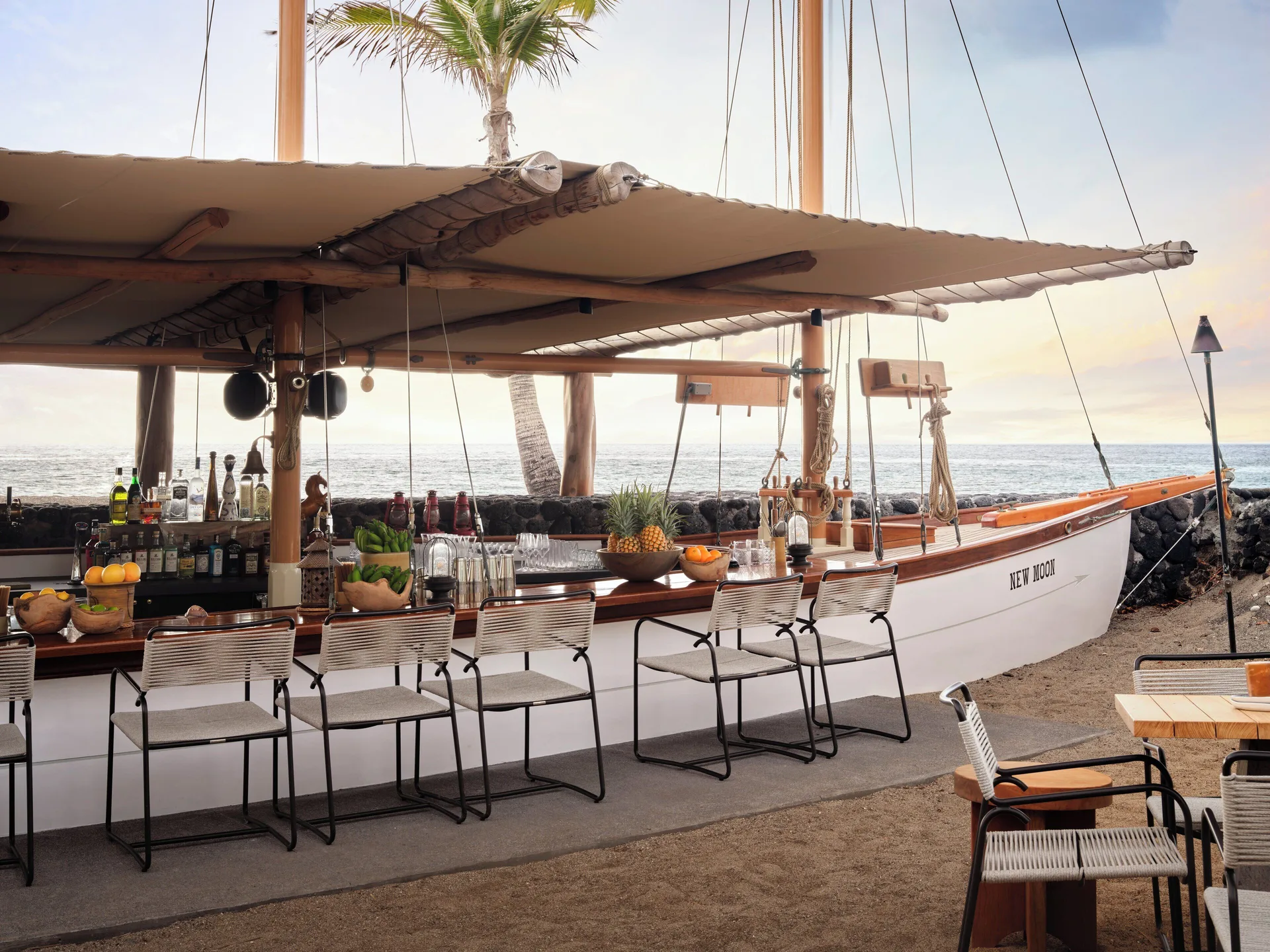 Boat-shaped oceanfront bar with stools facing the water at Kona Village.