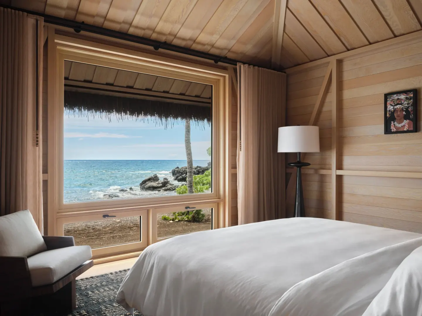 Beachfront guest room with bed and ocean view at Kona Village.