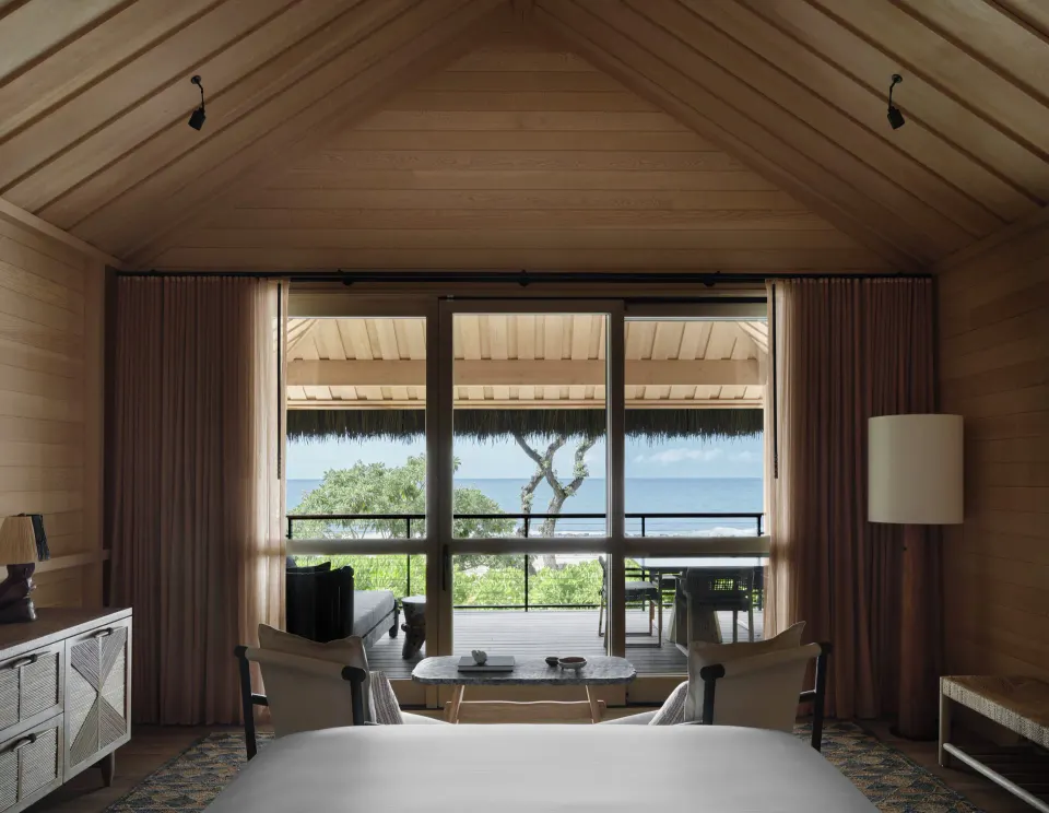 Beach Front Hale room with wood ceiling, bed, seating and ocean-facing lanai at Kona Village.