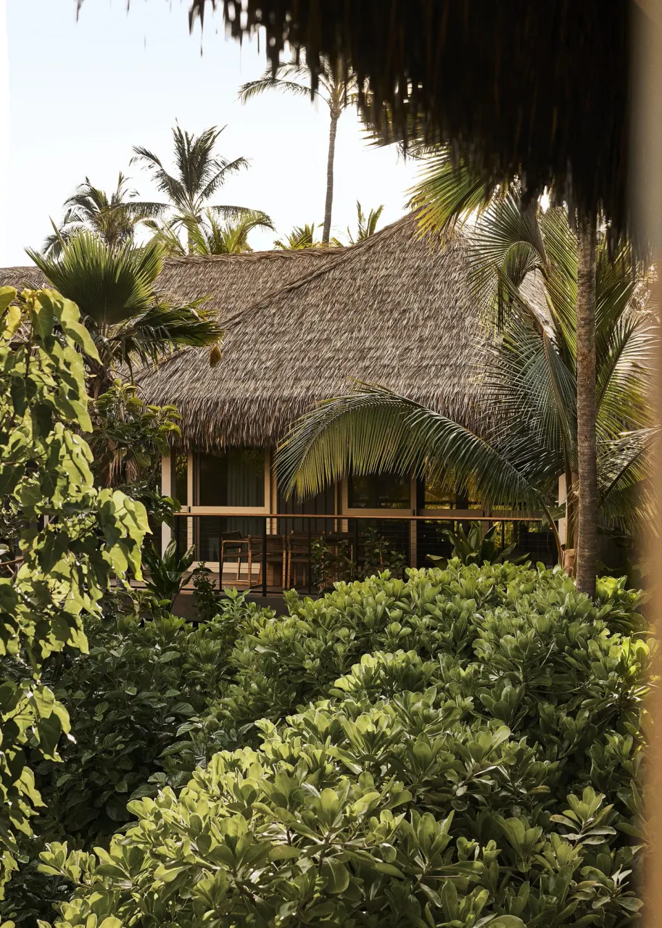 Garden View One Bedroom Kauhale exterior framed by palms and lush greenery at Kona Village.