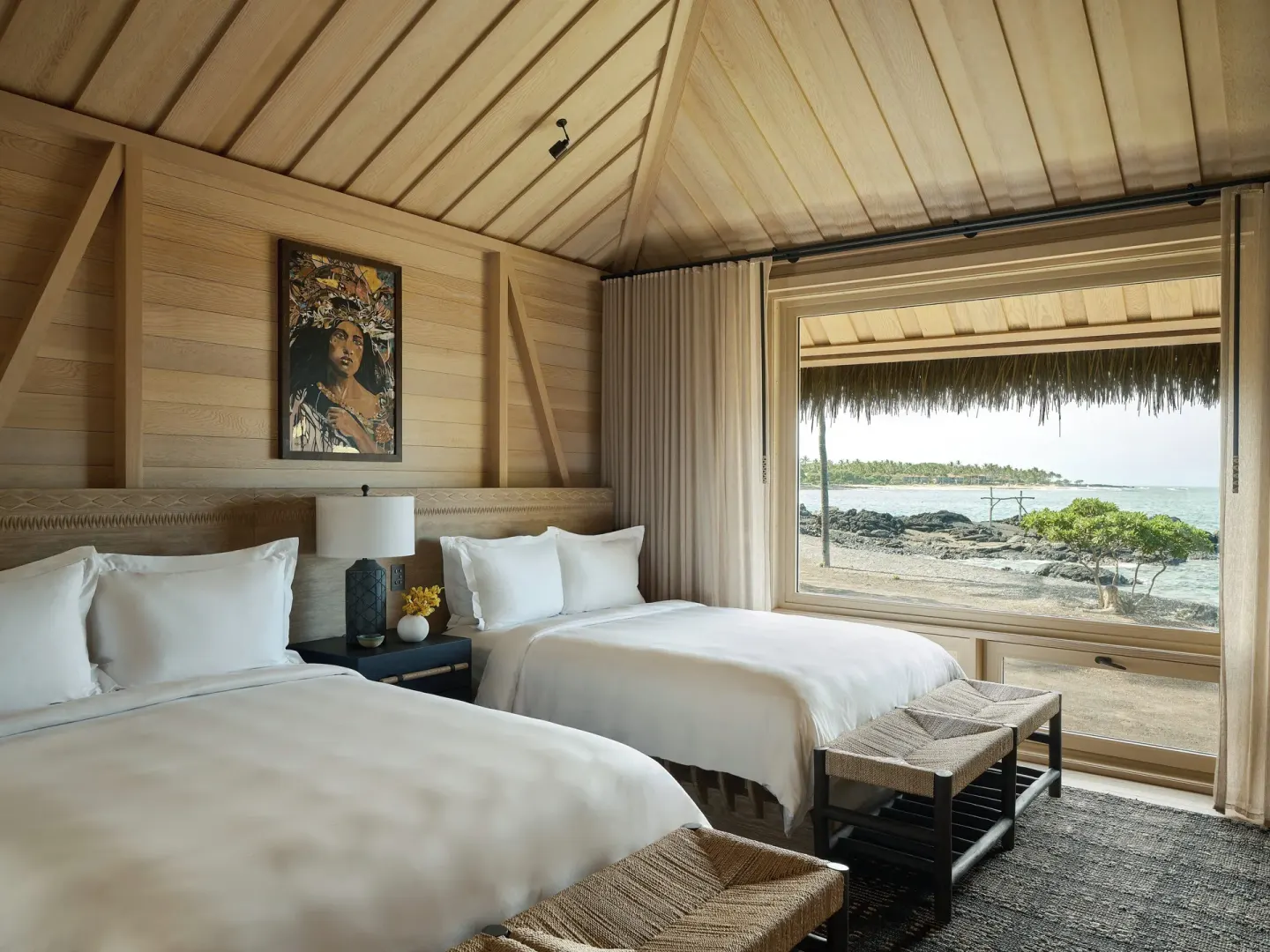 Two beds and ocean view in an Ocean Front Black Sand Two Bedroom Kauhale at Kona Village.