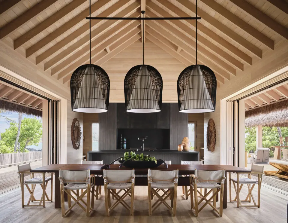 Dining table and open kitchen in Ocean Front Four Bedroom Maheawalu Kauhale at Kona Village.