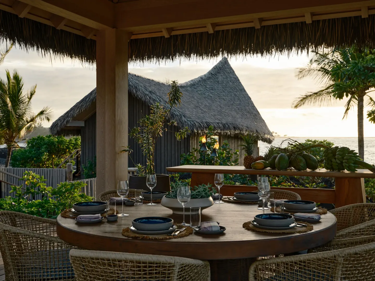 Outdoor dining table on a covered lanai at the Ocean Front Four Bedroom Maheawalu Kauhale at Kona Village.