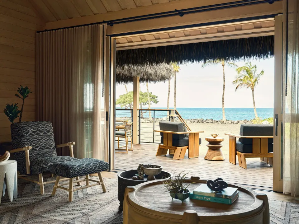 Ocean Front One Bedroom Kauhale sitting area with open doors to the ocean lanai at Kona Village.