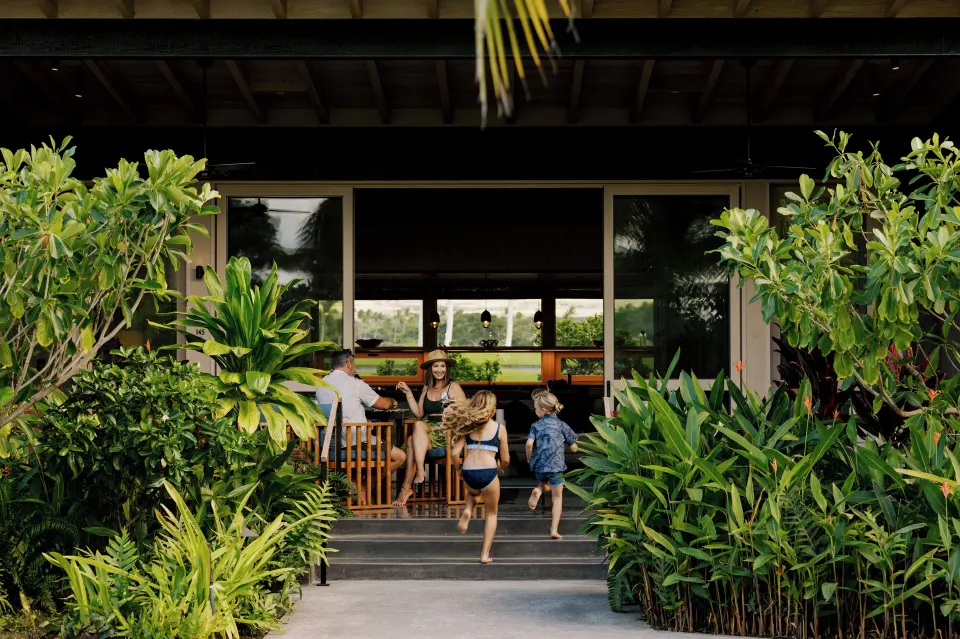 Family entering a lushly planted kauhale lanai at Kona Village.