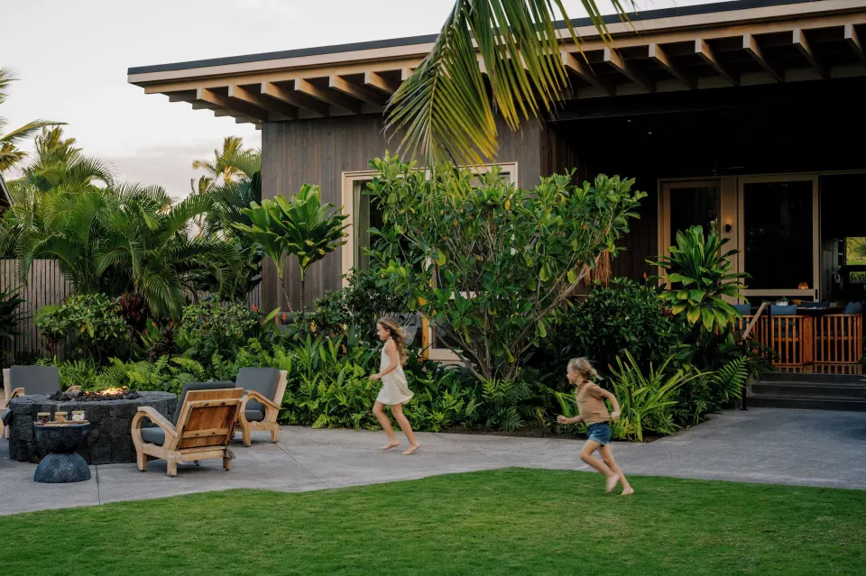 Children running across the lawn outside an Ohana Pool Kauhale at Kona Village.