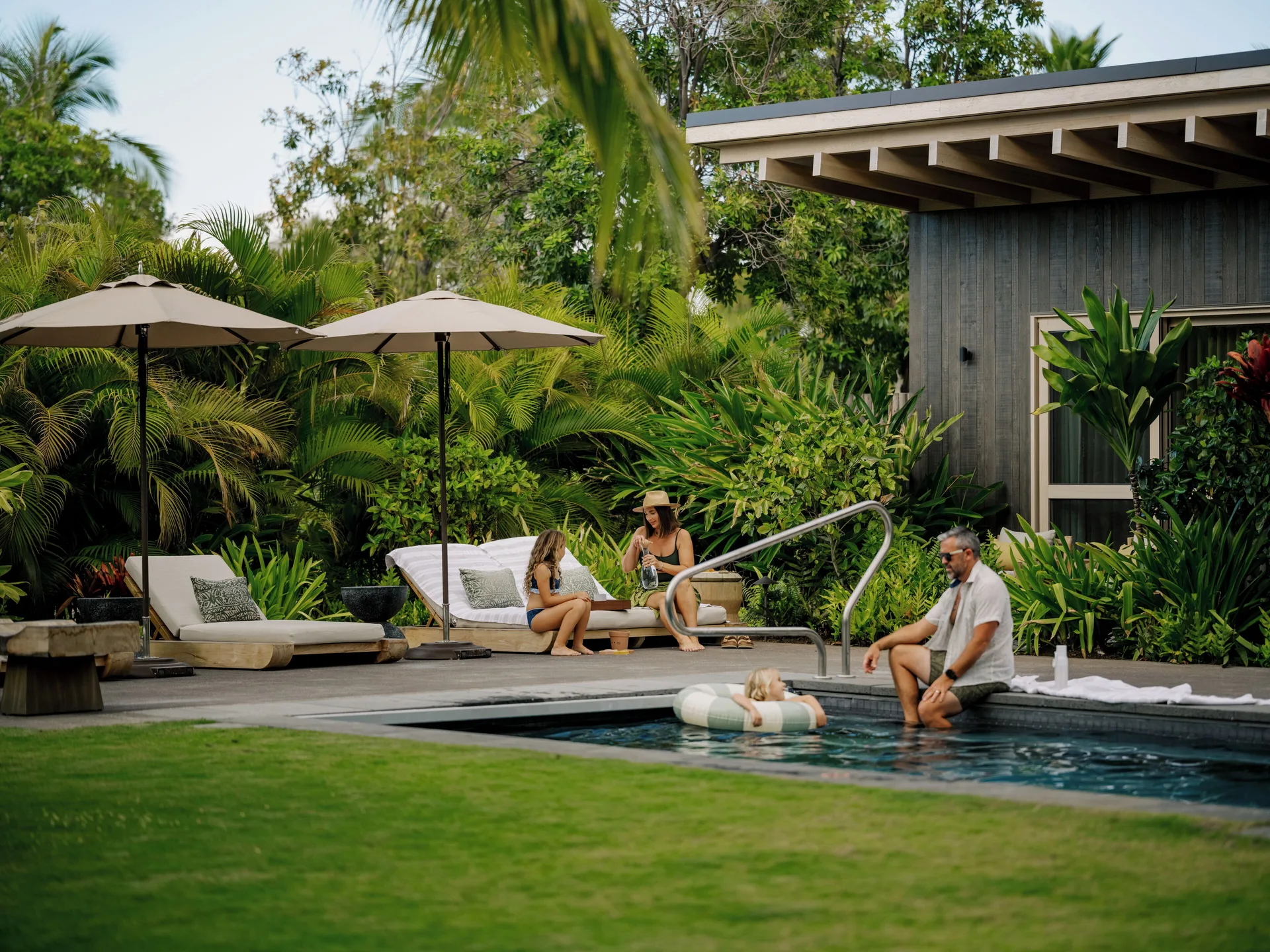 Family by the pool at the Ohana Pool Accessible Four Bedroom Kauhale at Kona Village.