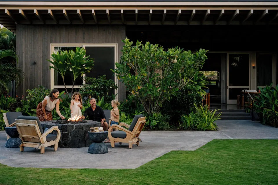Guests gather around an outdoor fire pit at the Ohana Pool Accessible Four Bedroom Kauhale at Kona Village.