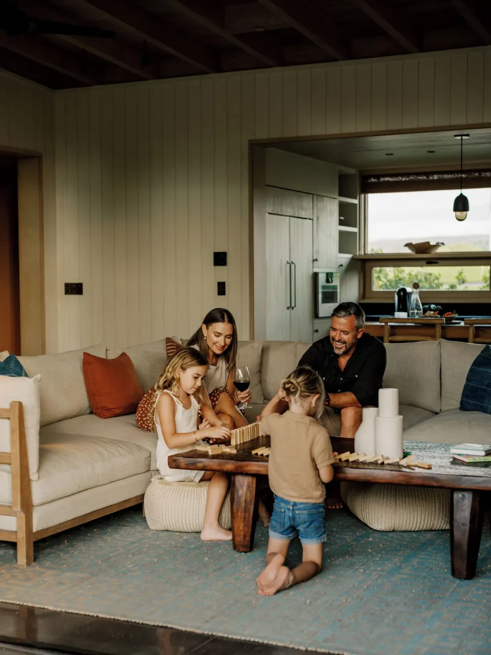 Family gathers in the living room of the Ohana Room Pool Four Bedroom Kauhale at Kona Village.