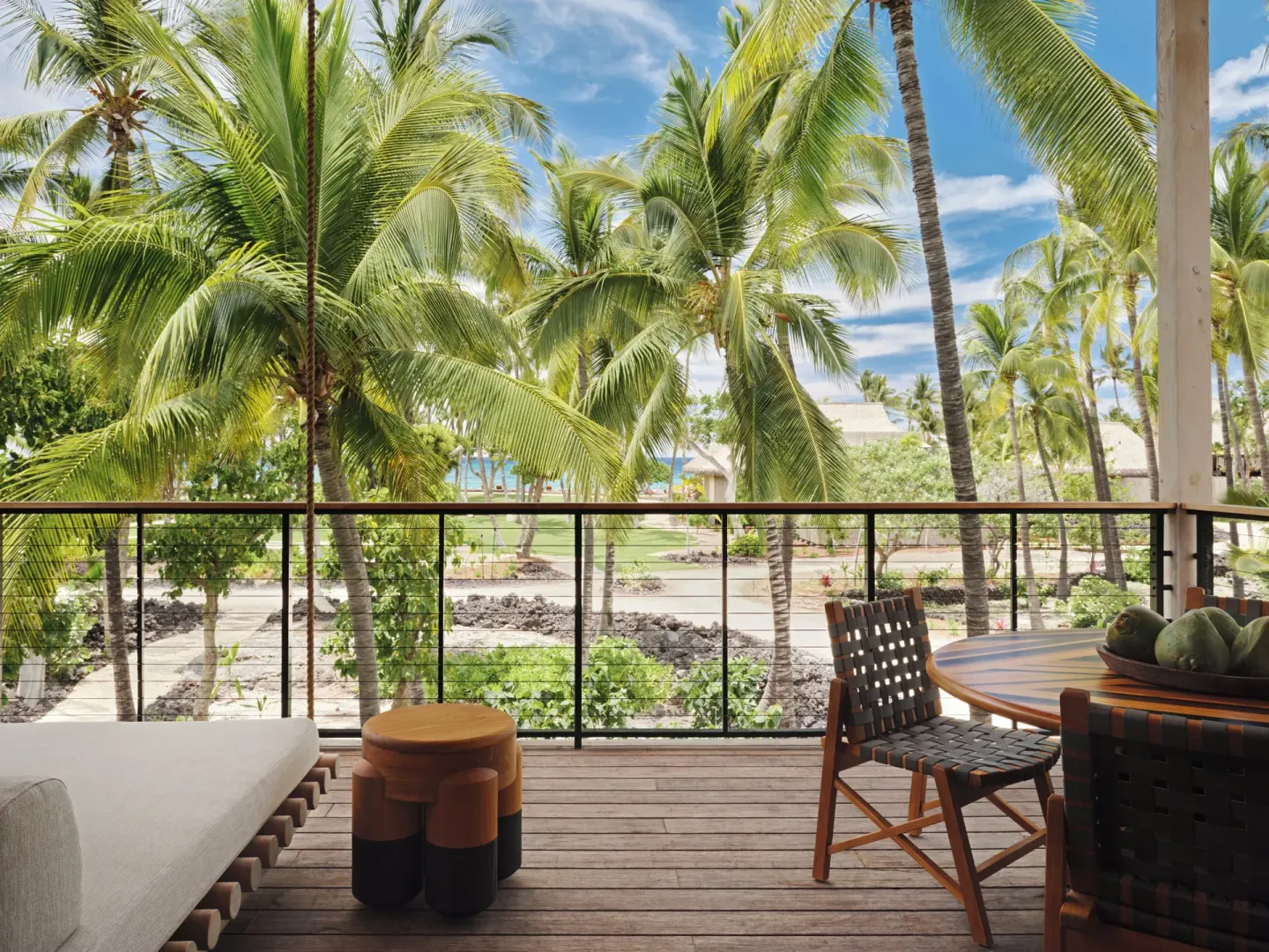 Tree Top Hale lanai at Kona Village with lounge seating, dining table, and palm views.