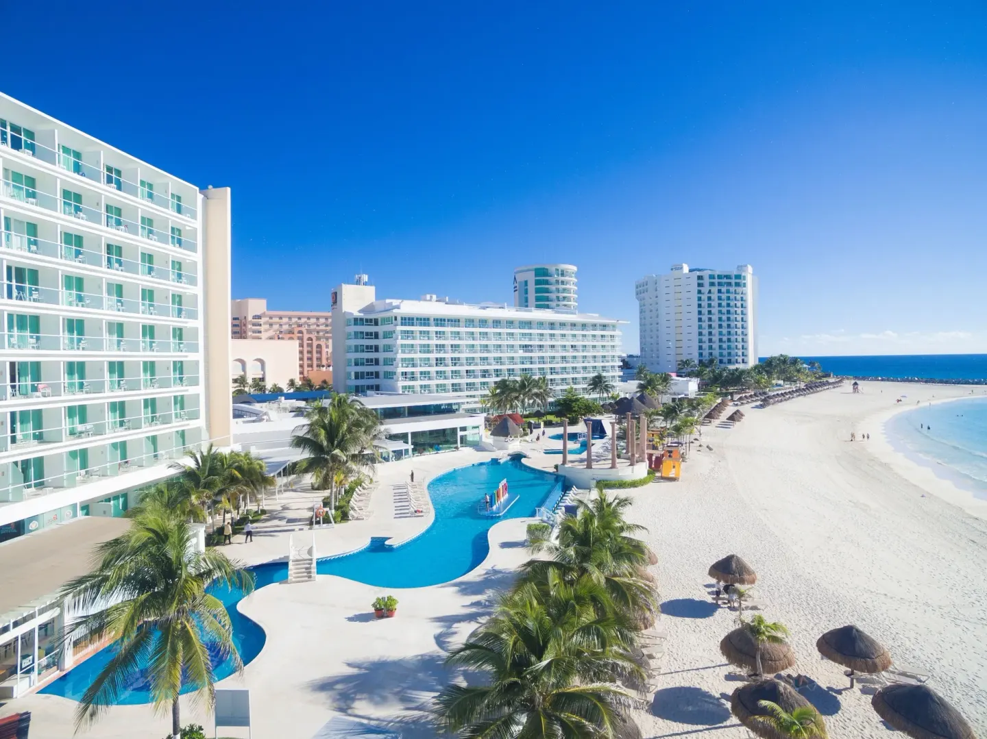 Beachfront towers, pool, palms and white sand at Krystal Cancun.