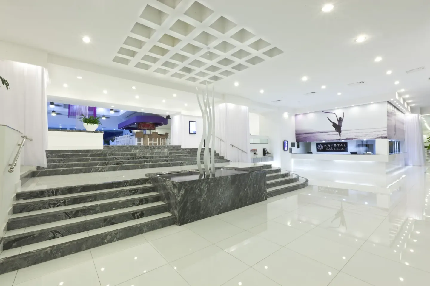 White lobby with marble stairs and reception desk at Krystal Cancun.