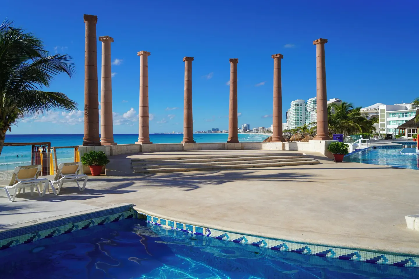Pool terrace with columns and oceanfront views at Krystal Cancun.