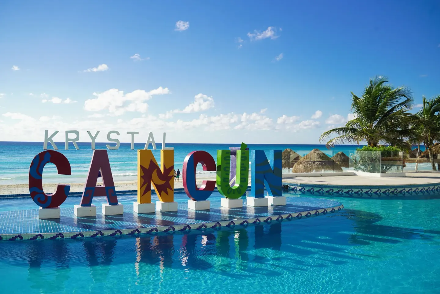 Krystal Cancun sign beside the pool with the beach beyond.