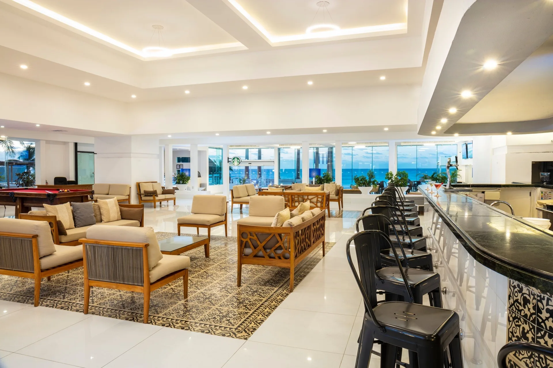 Lounge seating, bar stools and ocean-facing windows at Krystal Cancun.