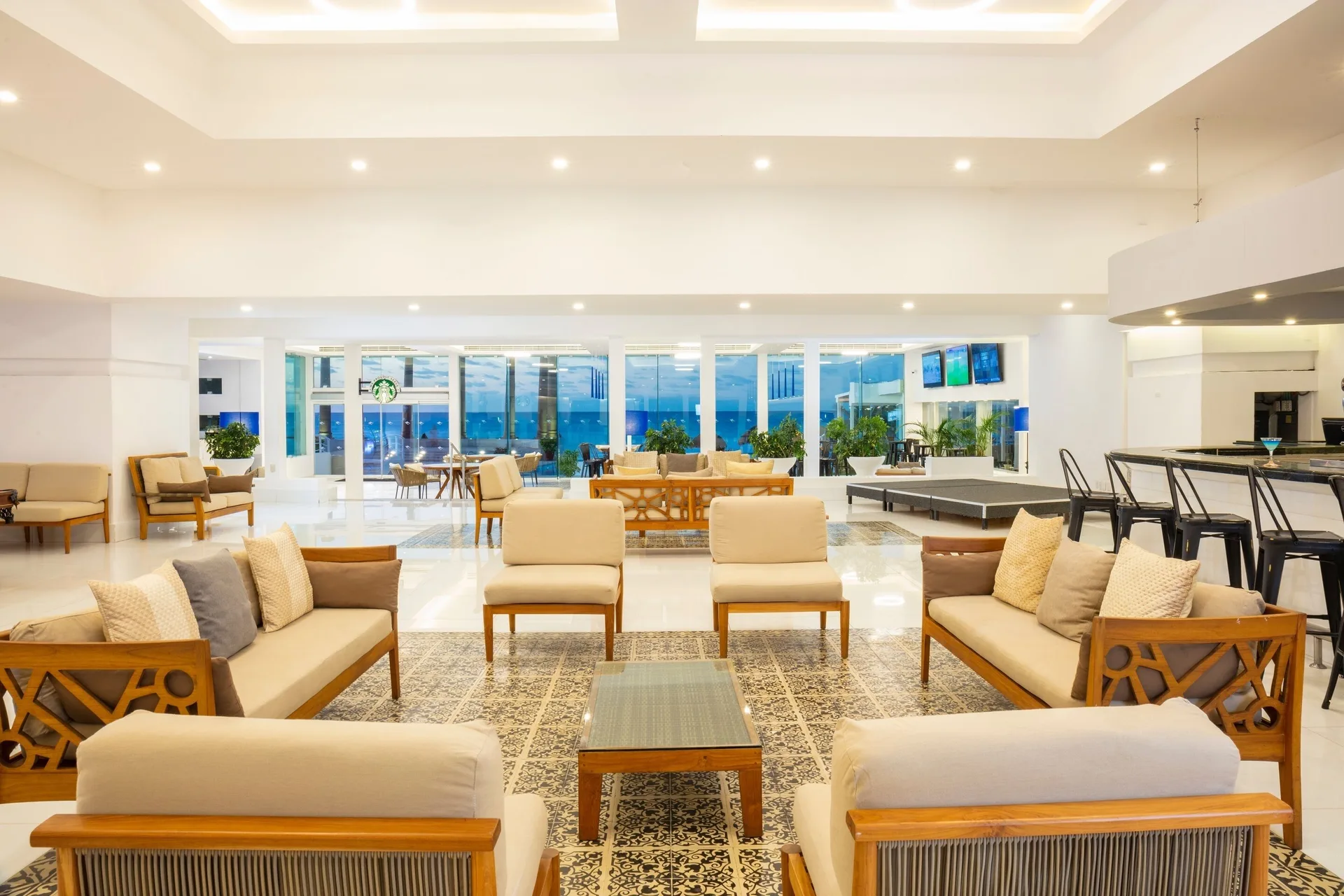 Sofas, armchairs and bar area in a bright lounge at Krystal Cancun.