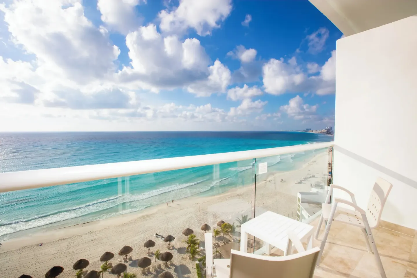 Club Room balcony with table, chairs, beach, and ocean at Krystal Cancun.