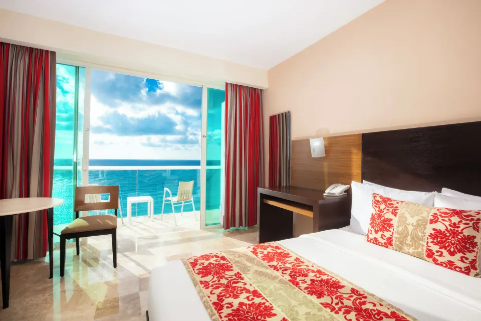 Club Room king bed beside balcony doors with ocean view at Krystal Cancun.