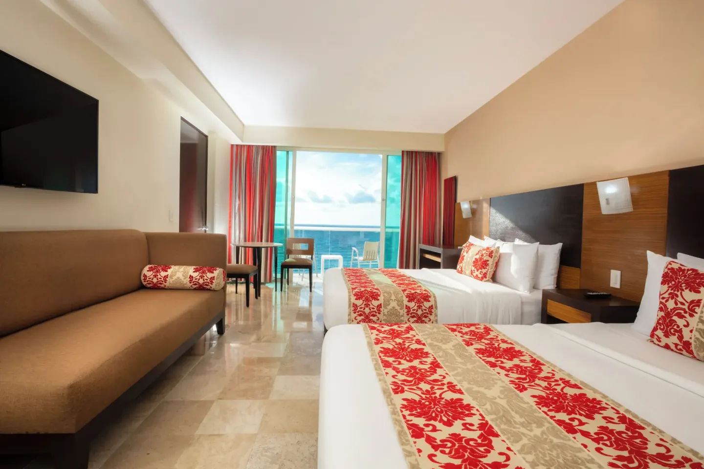 Guest room with sofa, TV, and furnished balcony at Krystal Cancun.