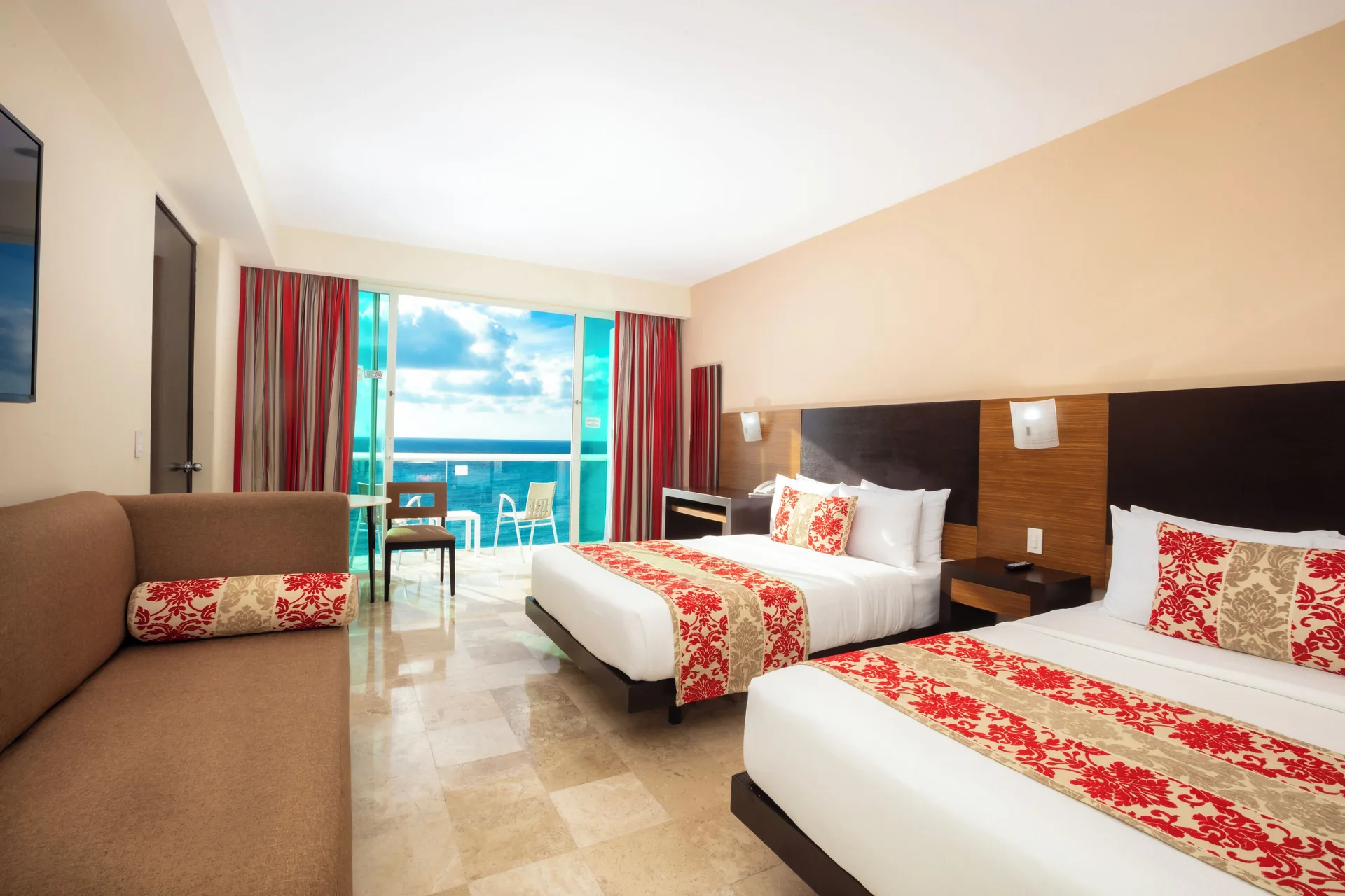 Guest room with two beds, sofa, and furnished balcony at Krystal Cancun.
