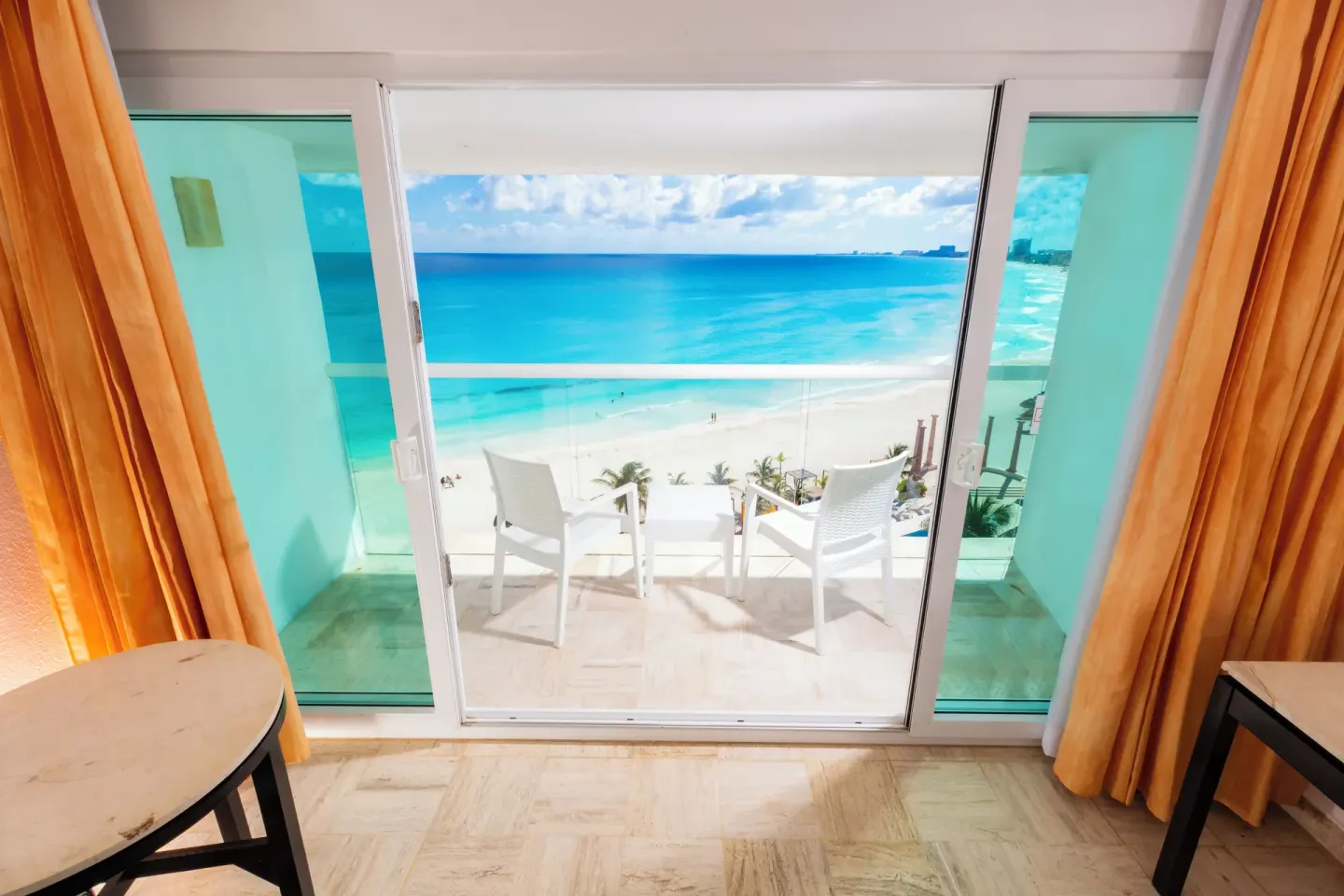 Balcony doors with beach and ocean view from a deluxe room at Krystal Cancun.