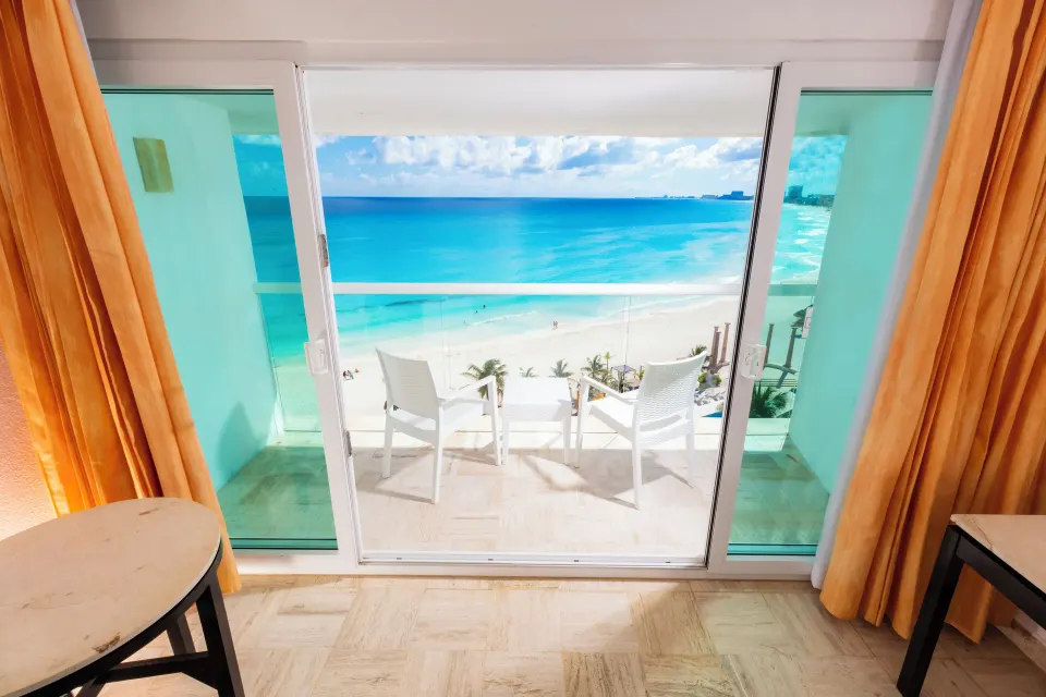 Balcony doors with beach and ocean view from a deluxe room at Krystal Cancun.