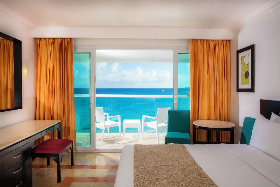 Deluxe ocean view room with king bed and balcony chairs at Krystal Cancun.