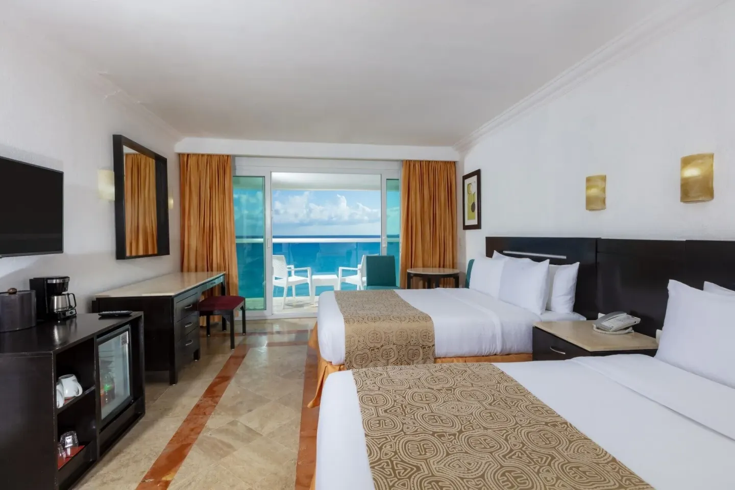 Deluxe ocean view two-bed room with TV and refreshment area at Krystal Cancun.
