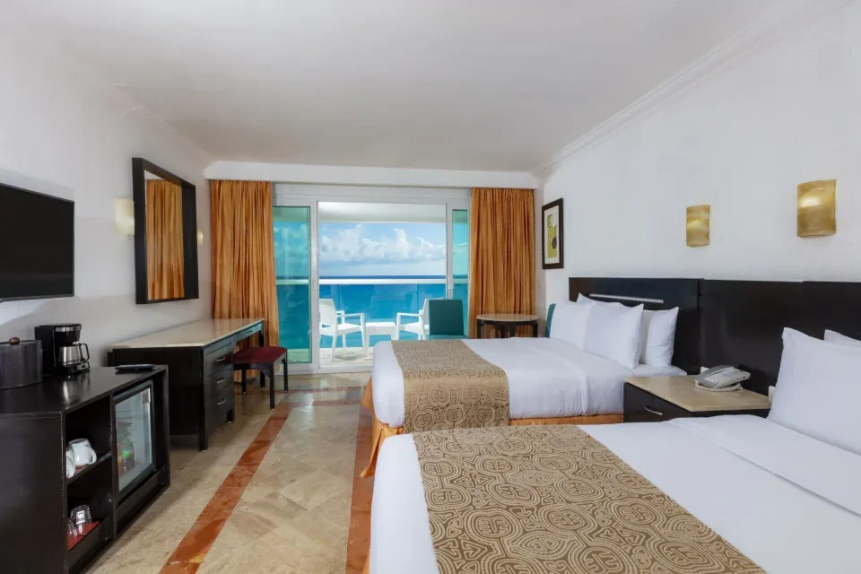 Deluxe ocean view two-bed room with TV and refreshment area at Krystal Cancun.