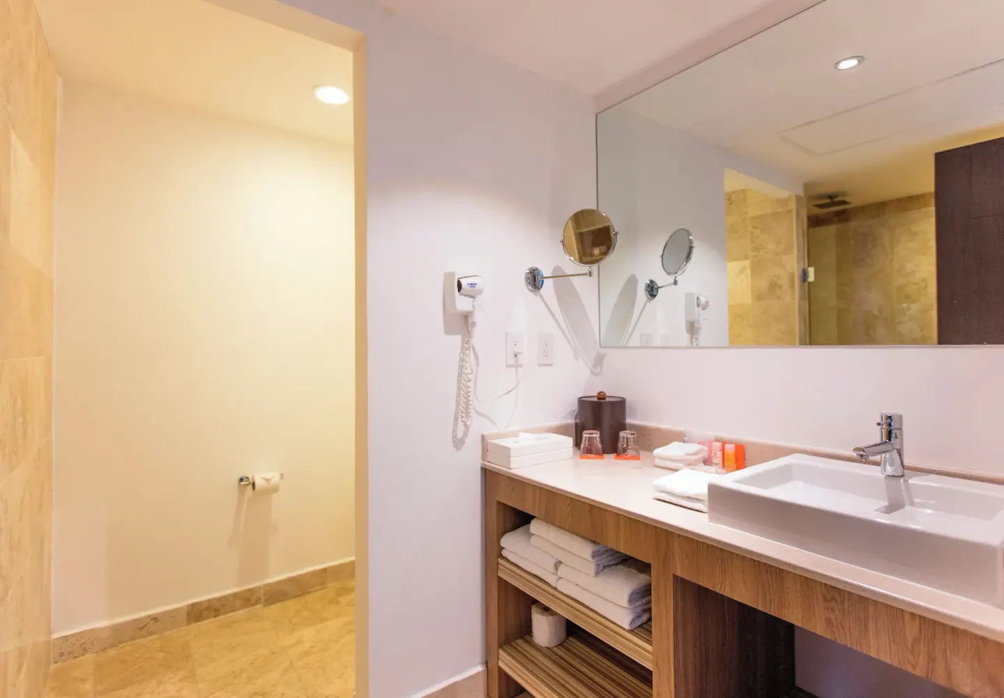 Family Studio bathroom vanity with sink, mirror, towels, and shower area at Krystal Cancun.