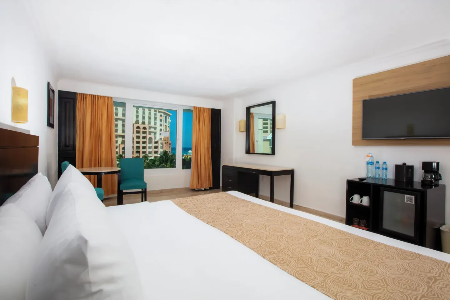 Standard Room king bed with city view window, desk, TV, mini fridge, and coffee maker at Krystal Cancun.