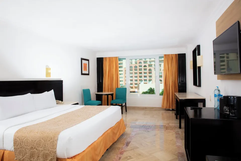 Standard Room with king bed, window seating, wall TV, and city-facing window at Krystal Cancun.