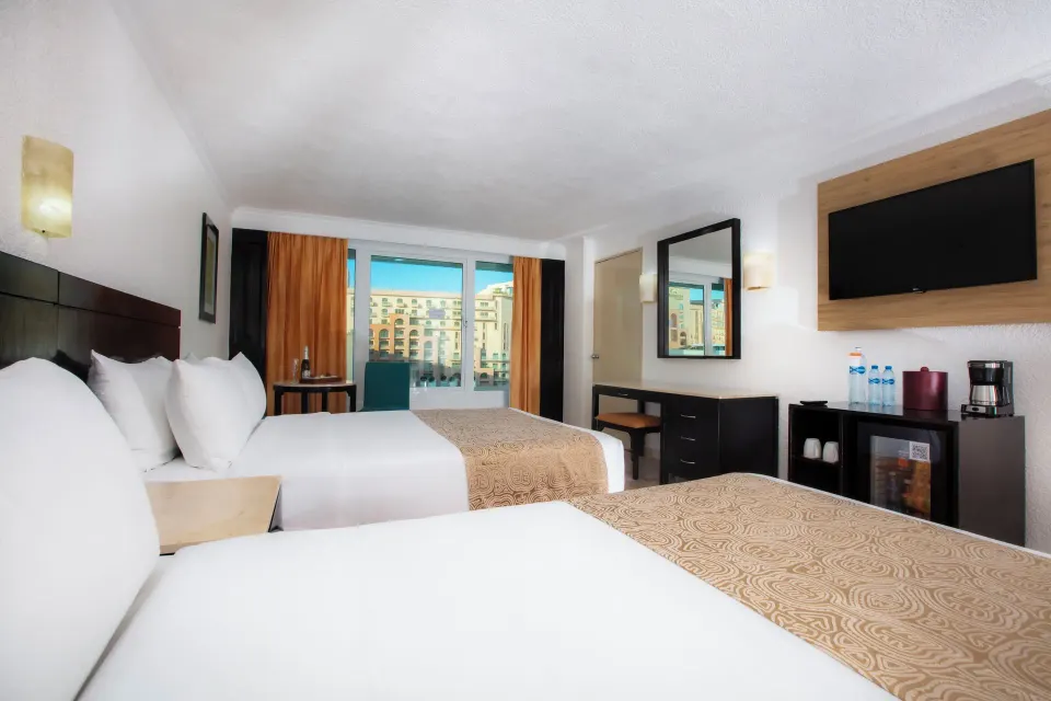 Standard Room with two beds, wall TV, mirror, desk, and city view window at Krystal Cancun.