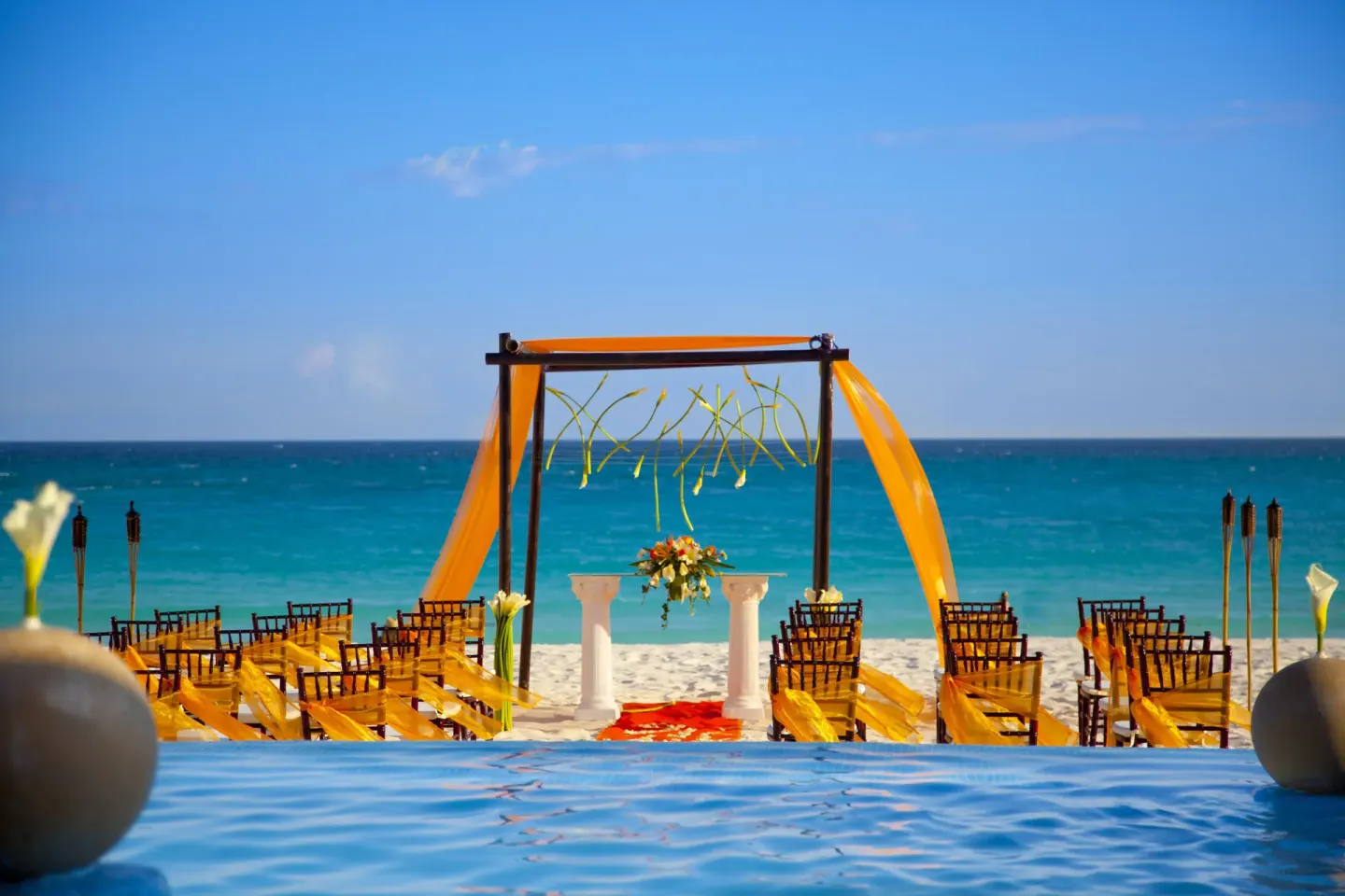 Beach wedding ceremony setup with yellow fabric and ocean backdrop at Krystal Cancun.