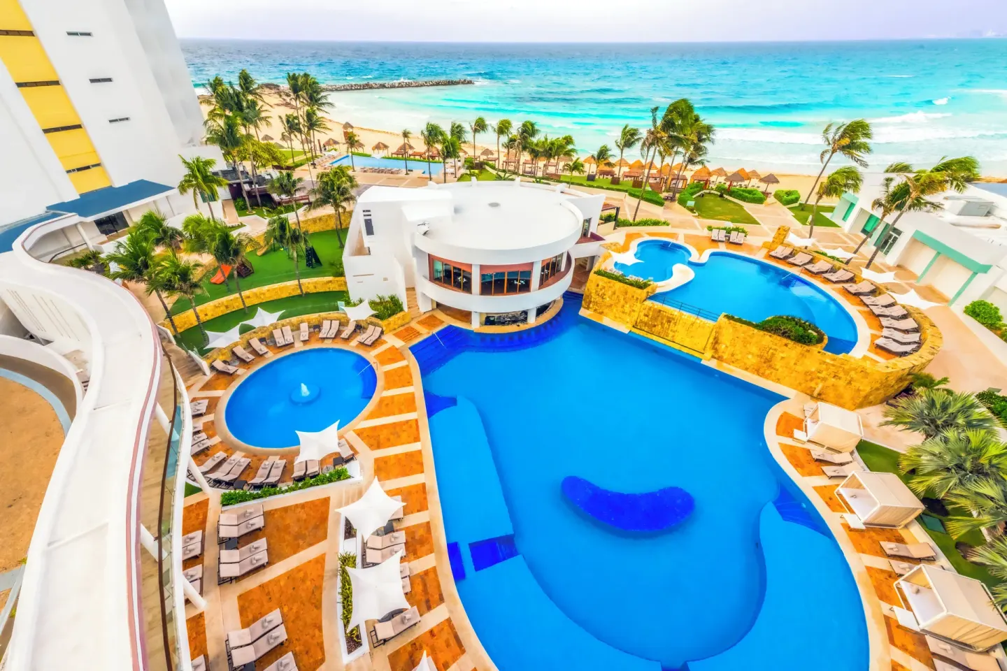 Aerial view of pools, loungers, palms, and beach at Krystal Grand Cancun.