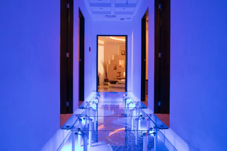 Blue-lit spa corridor with a glass floor at Krystal Grand Cancun.