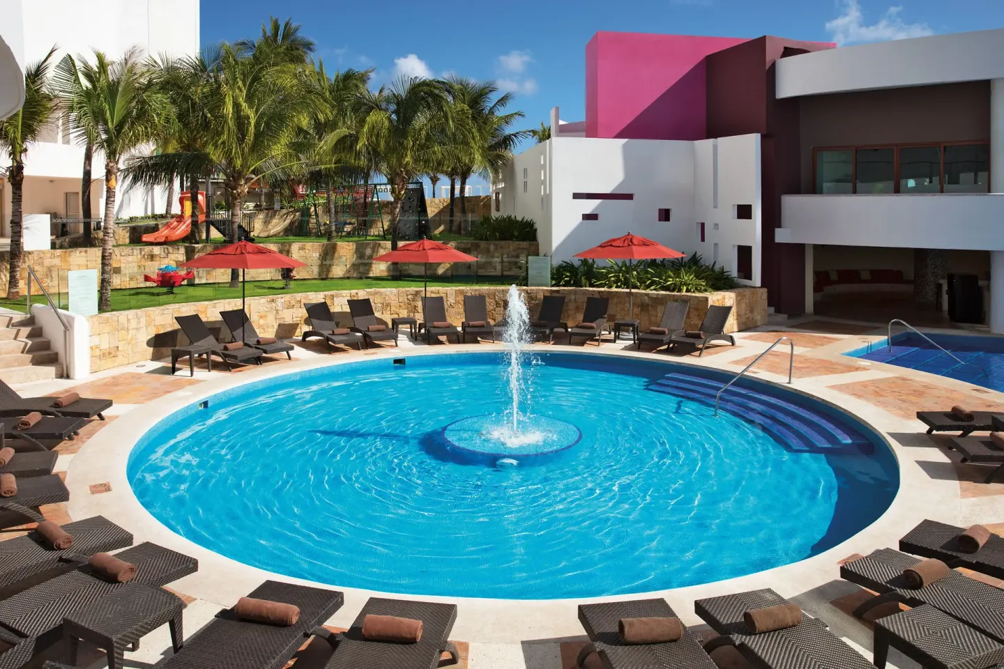 Circular pool with a fountain and loungers at Krystal Grand Cancun.