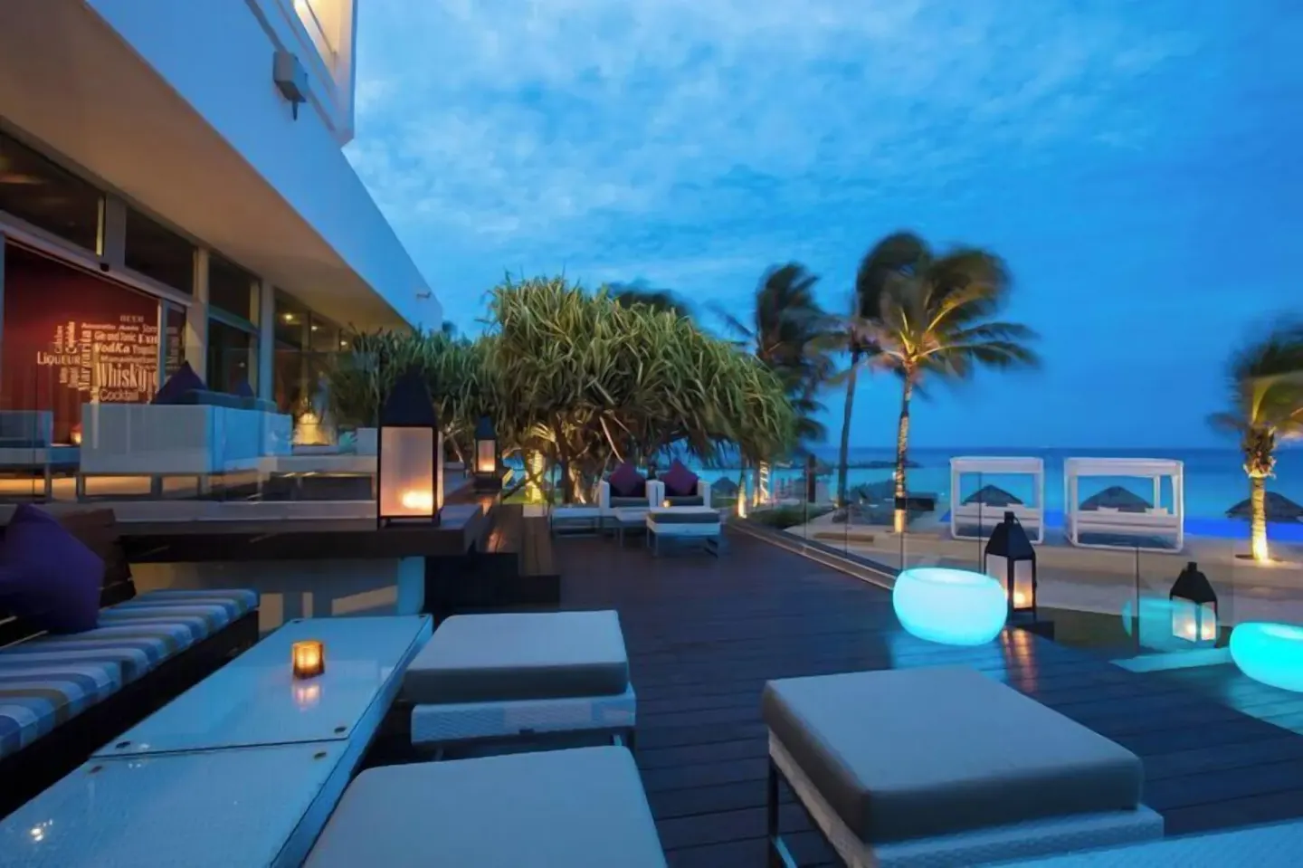 Evening oceanfront lounge terrace with glowing lights at Krystal Grand Cancun.