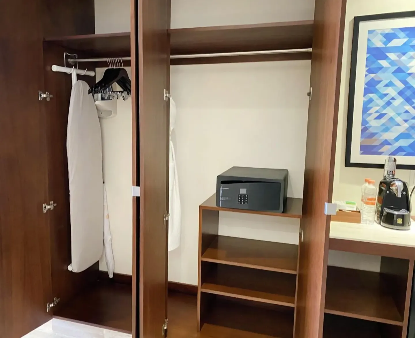 Guest room closet with ironing board, hangers, safe, and coffee area at Krystal Grand Cancun.