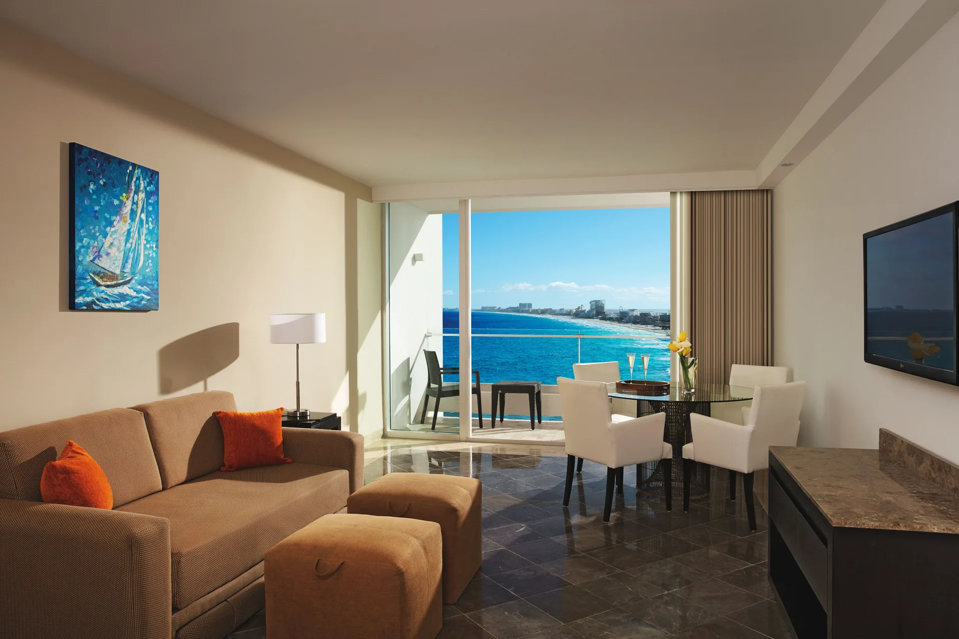 Living area with sofa, dining table, balcony, and ocean view at Krystal Grand Cancun.
