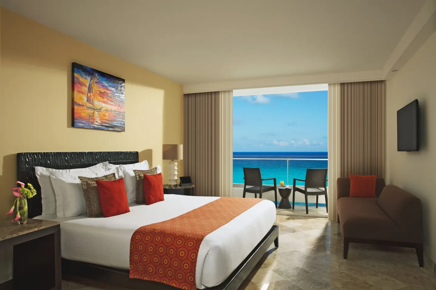 King-bed guest room with balcony seating and ocean view at Krystal Grand Cancun.
