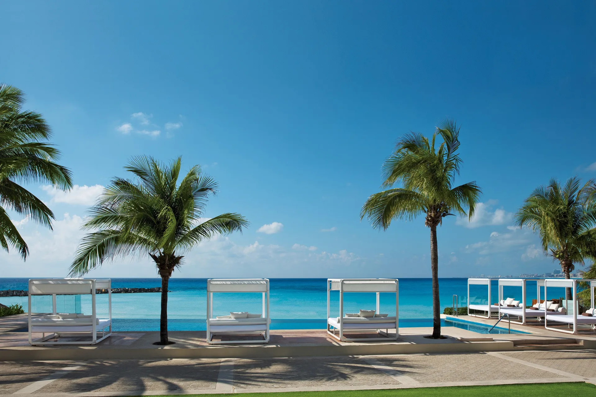 Poolside cabanas and palm trees facing the ocean at Krystal Grand Cancun.
