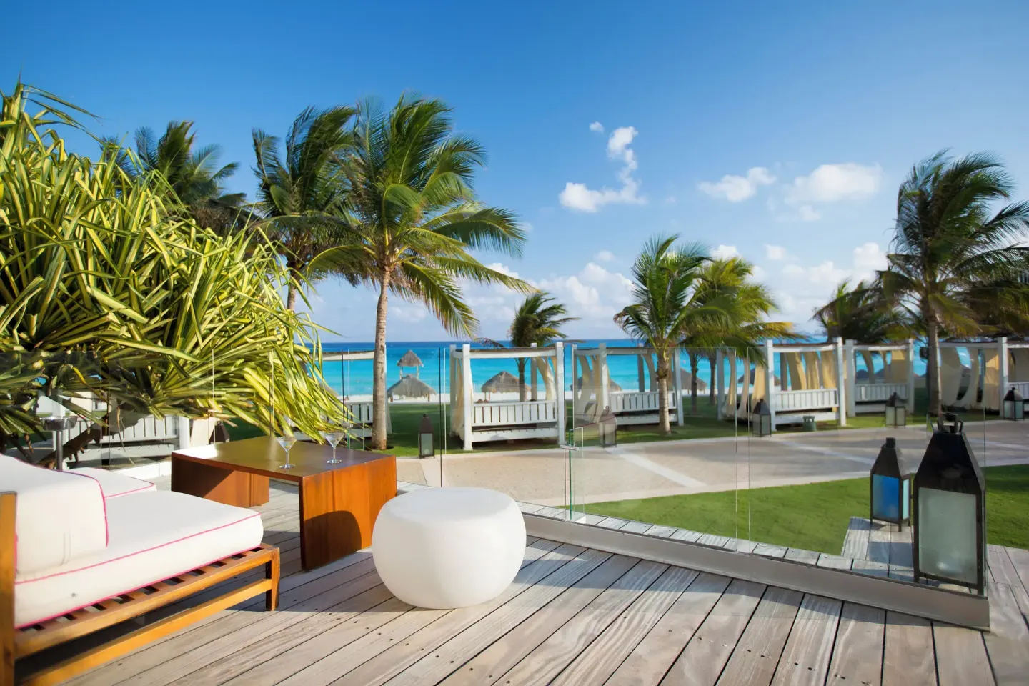 Oceanfront terrace seating with palm trees at Krystal Grand Cancun.