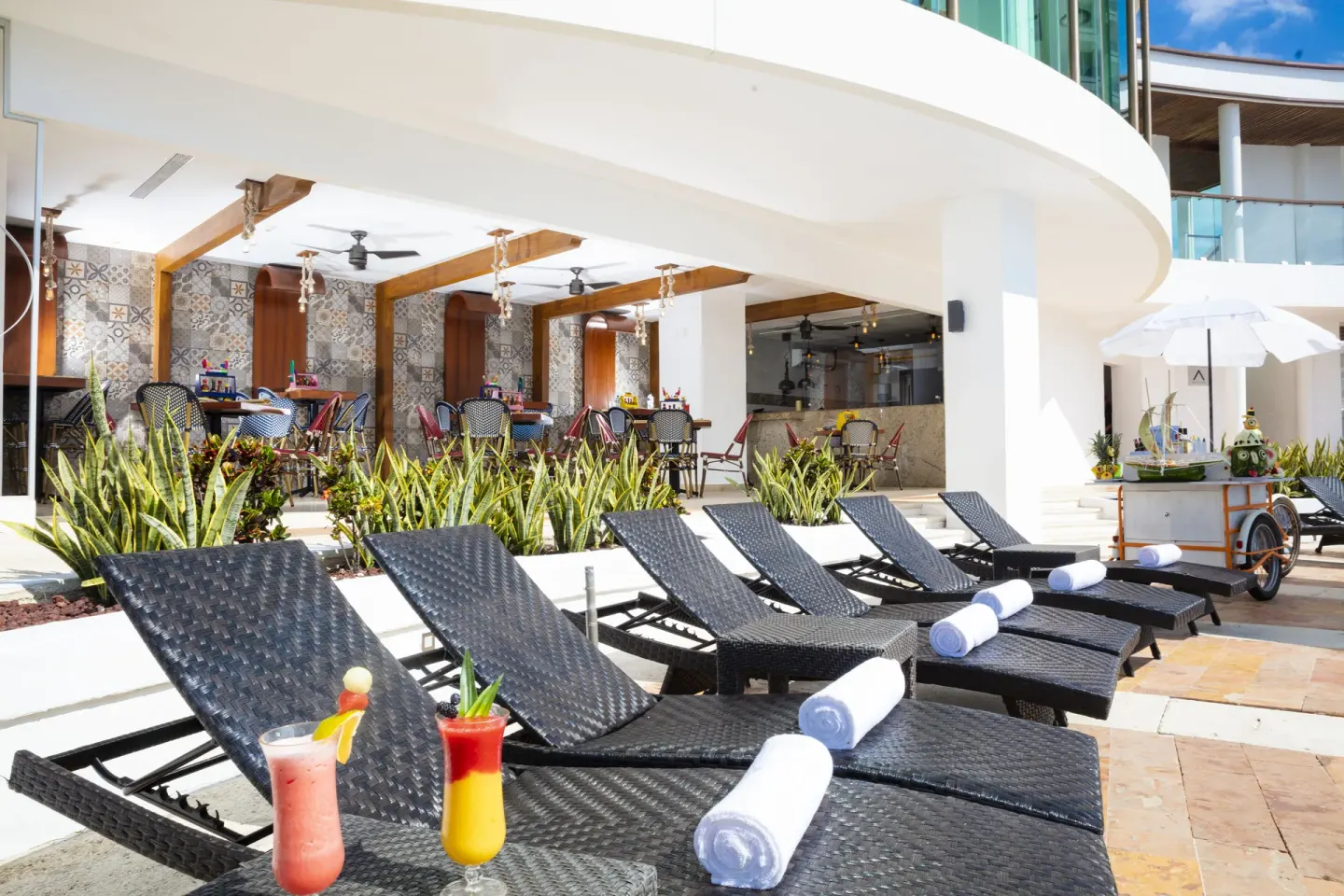 Chaise lounges with cocktails beside the pool terrace at Krystal Grand Cancun.