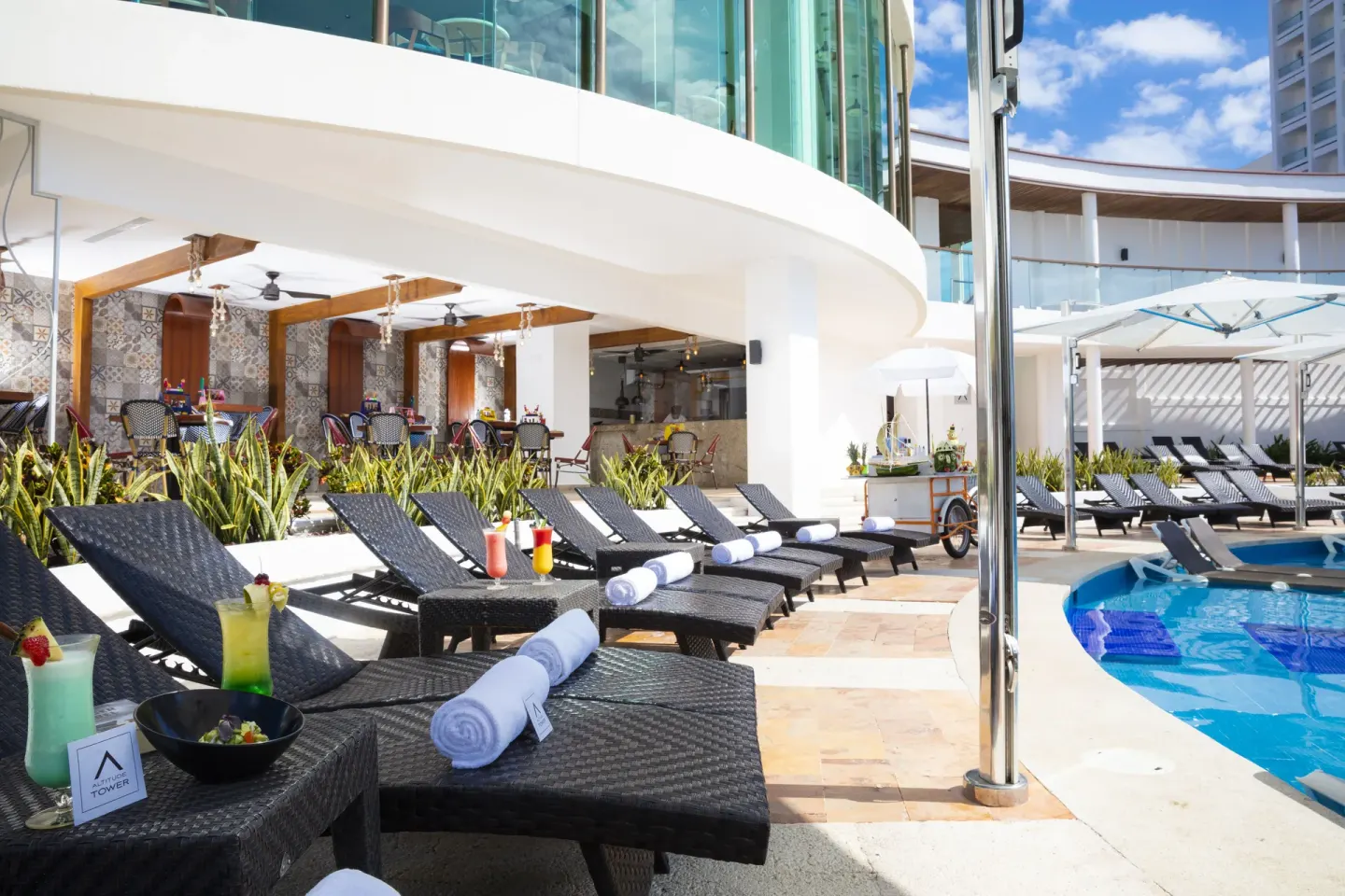 Poolside loungers with drinks and towels at Krystal Grand Cancun.