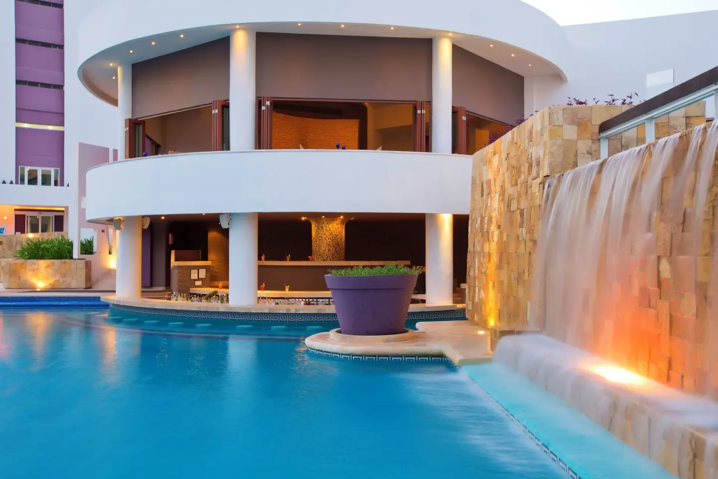 Poolside waterfall and curved building beside the pool at Krystal Grand Cancun.